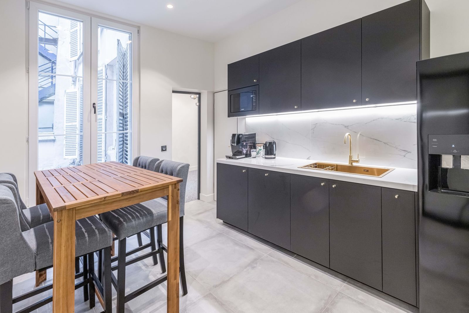 Cuisine équipée, table haute et fenêtre sur cour